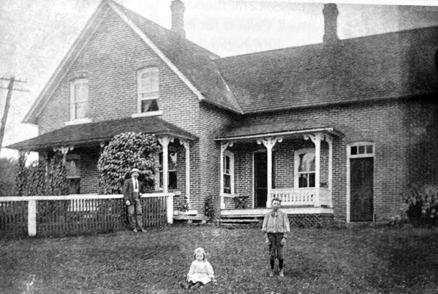 Photo d'époque de la maison de brique du 1 rue Bishop vers 1910, avec Milan Bishop et ses deux enfants devant la galerie
